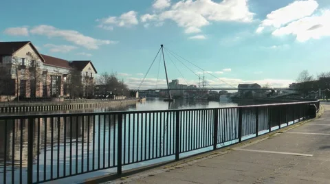 Urban riverside path with footbridge over the river, modern offices, tall ship Stock Footage 1064616