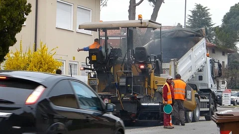 Urban road under construction, asphalting in progress. Worker with a shovel Stock Footage 87084187