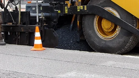 Urban road under construction, asphalting in progress. Worker in orange uniform Stock Footage 112660195