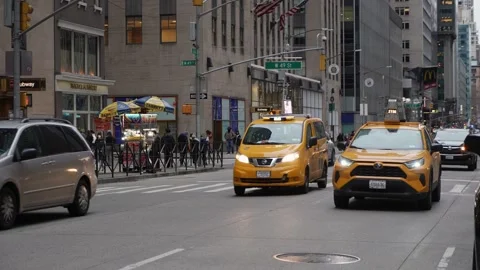 An Urban Scene Featuring a Bright Yellow Taxi Navigating through a Busy City Stock Footage 303872018