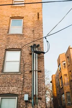 In an urban setting, electrical wires run along the side of a brick building  Photos