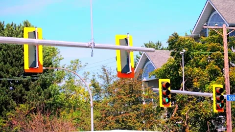 Urban Traffic Lights Hanging from Horizontal Mast Arm Against Houses and Trees Stock Footage 341580800