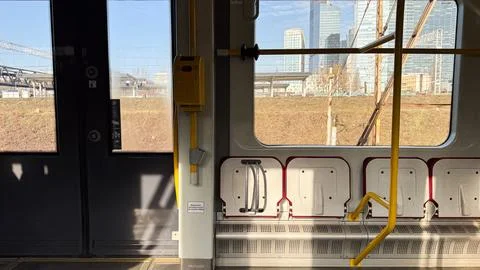 Urban train interior with sunlit windows and modern cityscape in background.. Stock Photos