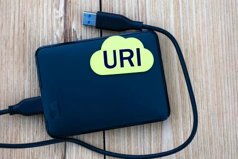 URI - word on a note sheet lying on an external drive on a wooden background Stock Photos