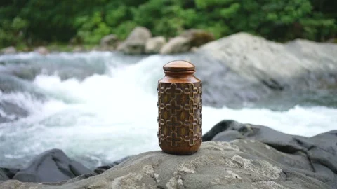 Urn for ashes after cremation on the background of a mountain river Stock Footage 247274131