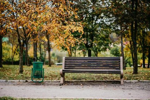 An urn next to an empty park bench. Stock Photos