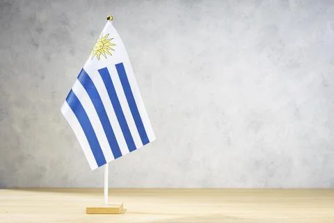 Uruguay table flag on white textured wall. Copy space for text, designs or 스톡 일러스트