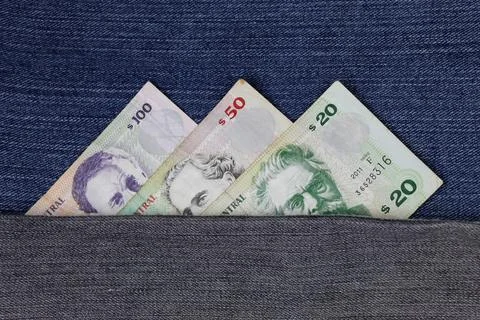 Uruguayan banknotes of different denomination between blue denim fabric Stock Photos