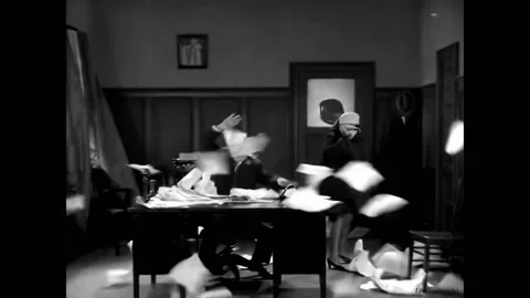 US - 1928 - in this silent comedy, a man aims a fan at a desk and gets all the Stock Footage 301520737