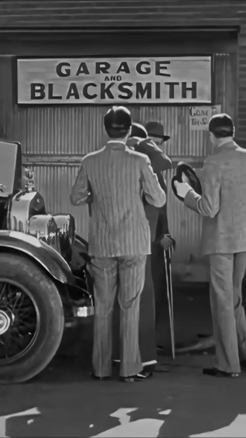 US - 1928 - in this silent comedy, men push a car to a workshop but the mechanic Stock Footage 340199328