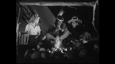 US - 1935 - in this western, a boy and a girl sit by a campfire with a Native Stock Footage 340591116