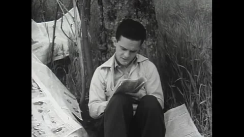 US - 1941 - A pair of men read about a job application in the news. Stock Footage 340585876