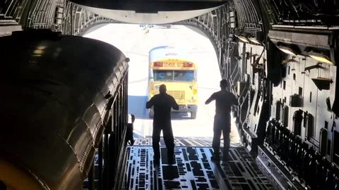 U.S. Air Force airman directing school bus onto ramps of C-17 Globemaster Stock Footage 213922834