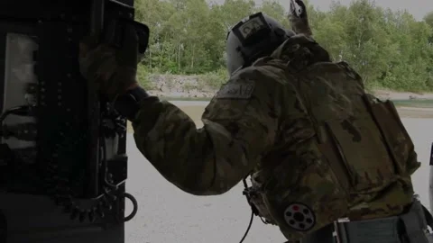 U.S. Air Force airman looking out from helicopter hovering above river Видео 213580768
