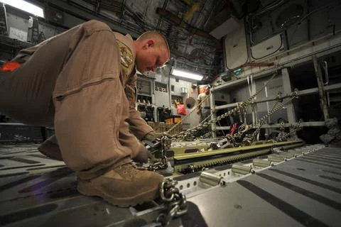 U.S. Air Force loadmaster Staff Sgt. Chris Rapp ties down chains to a buff... Stock Photos