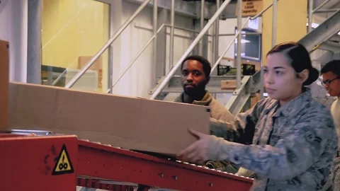 U.S. Air Force post office workers off-loading packages from conveyor Stock Footage 103582193