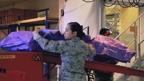 U.S. Air Force post office workers unloading packages from conveyor Stockbeeldmateriaal 103586329