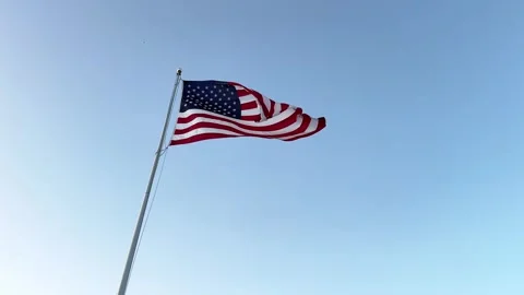 US American flag waving in the wind with a blue sky in background Stock Footage 252686597