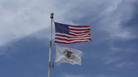 US and Illinois state flags waving in the wind against a blue sky Stock Footage 338119449
