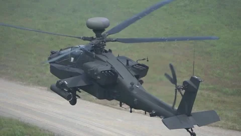 U.S. Army AH-64 Apache helicopter hovering above dirt track Stock Footage 282354509