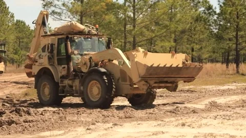 U.S. Army backhoe loader travelling over rutted sandy road 動画素材 271338367