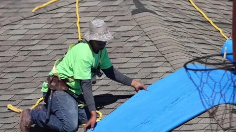 U.S. Army engineer positioning sheeting during blue roof installation Stock Footage 162308278