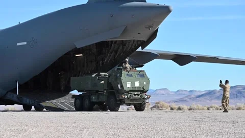 U.S. Army HIMARS driving off U.S. Air Force C-17 Globemaster III in desert Stock Footage 294679946