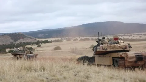 U.S. Army M1A2 Abrams tanks move along a dirt track during training operations Stock Footage 334781321