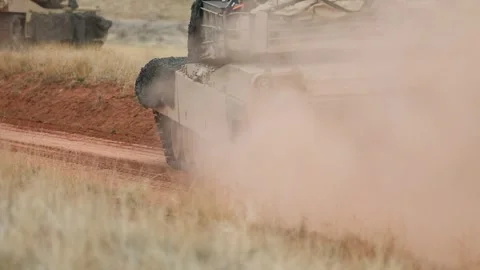 U.S. Army M1A2 Abrams tanks kick up dust as they move along a dirt track Stock Footage 334781323