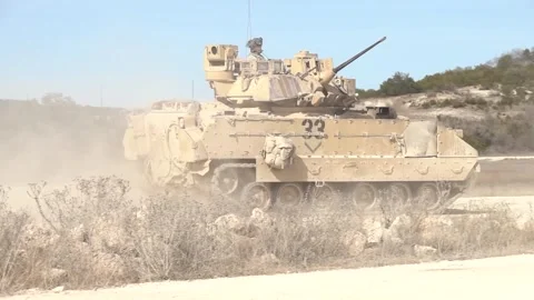 U.S. Army M2 Bradley Fighting Vehicle kicking up dust travelling on dirt road Stock Footage 262617767