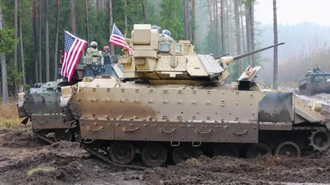 U.S Army M2A3 Bradley Fighting Vehicle parked in a wet, muddy forest clearing Stock Footage 294179565