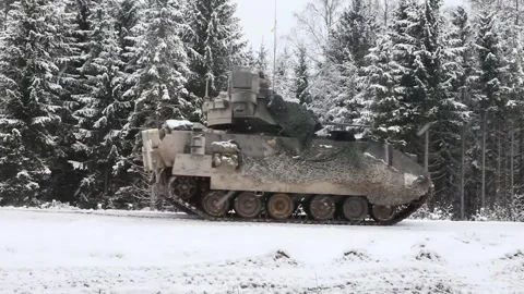 U.S. Army M2A4 Bradley IFV travelling through snow covered forest Stock Footage 301195396
