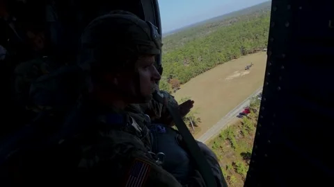 U.S. Army paratrooper looking out from UH-60 Blackhawk prior to parachute jump Stock Footage 263110674