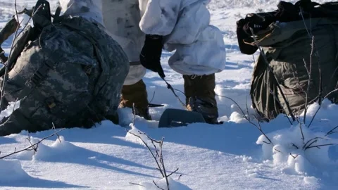 U.S. Army paratrooper putting boot into snow shoes in Artic wilderness Stock Footage 264491475