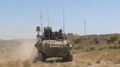 An US army soldier driving on top of a camouflaged tank in Afghanistan Stock Footage