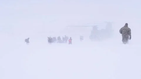 U.S. Army soldier wading through snow toward CH-47 Chinook helicopter Stock Footage 262312418