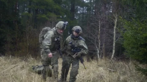 U.S. Army soldiers pulling casualty on tactical stretcher along forestry path Stock Footage 264755925