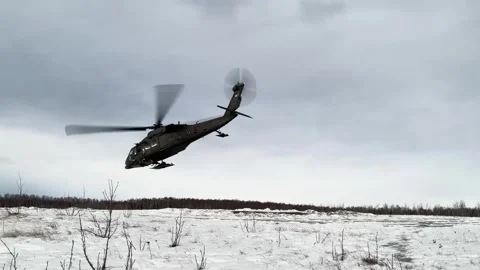 U.S. Army UH-60 Black Hawk with snow skis taking off from snow-covered landscape Stock Footage 295350145