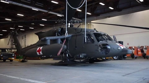 U.S. Army UH-60 Black Hawk Medevac with snow skis fitted being towed from hangar Stock Footage 299797600