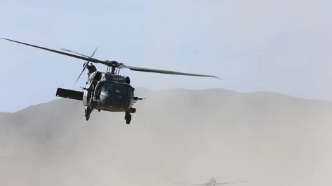 U.S. Army UH-60 Blackhawk creating sand storm on take-off in desert Stock Footage 268824176
