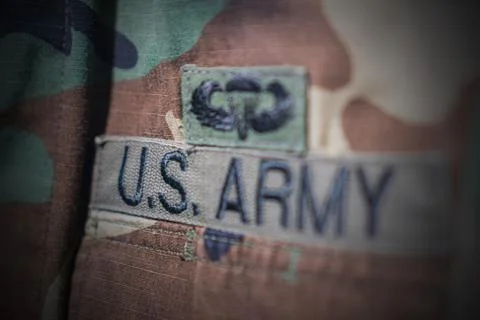 U.S. Army uniform patch close-up, bold letters on light fabric, smaller insig Stock Photos