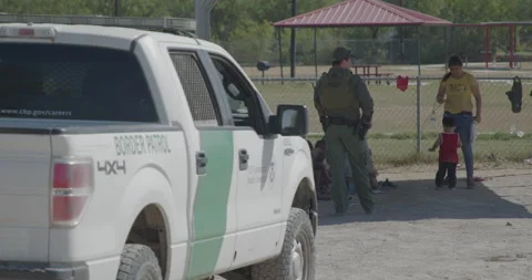 A US Border Patrol Agent supervises recently detained migrants who crossed Stock Footage 202454357