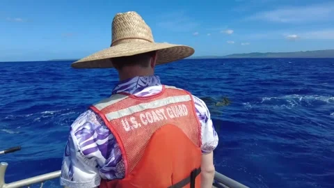 U.S. Coast Guard approaching crates floating in the ocean by boat Stock Footage 295033926