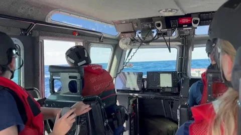 U.S. Coast Guard approaching migrants in makeshift boat Stock Footage 234407424