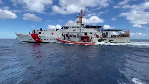U.S. Coast Guard high speed law enforcement boat sailing alongside USCG Cutter Stockbeeldmateriaal 234407516