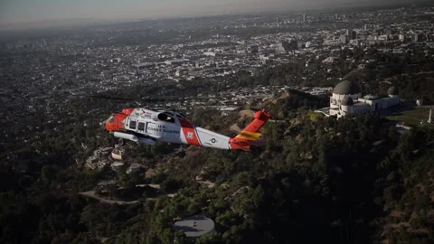 U.S. Coast Guard MH-60 Jayhawk flying over Griffith Observatory, Los Angeles Stock Footage 295775055