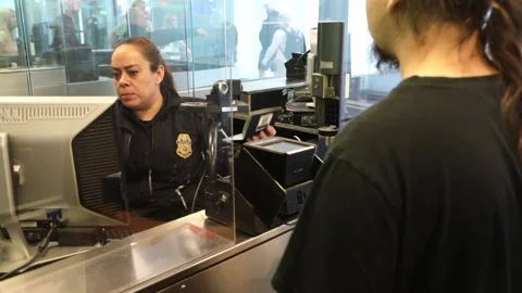 U.S. Customs and Border Protection officers processing passenger at airport 库存影片 295113238