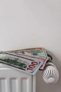 US dollar banknotes on central heating radiator with thermostat valve Photos