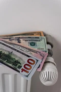 US dollar banknotes on central heating radiator with thermostat valve Fotos Stock