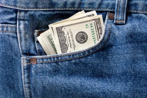 US dollar banknotes in the front left pocket of blue jeans. Concept of saving Stock Photos